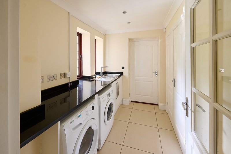 A dedicated utility and laundry room providing practical facilities for longer stays and larger groups. It includes washing machines, generous worktop space, a sink and storage.