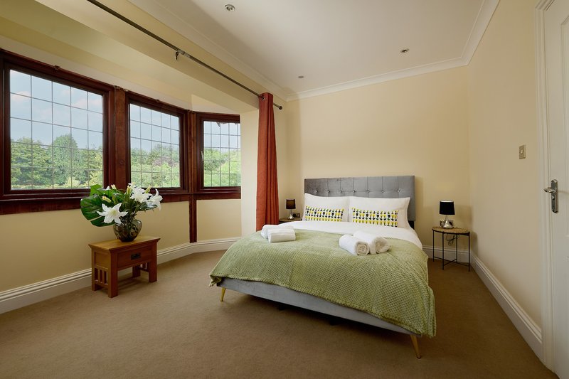 A spacious, light-filled double bedroom with large windows overlooking the surrounding countryside. It offers a peaceful place to relax and recharge after a busy day.