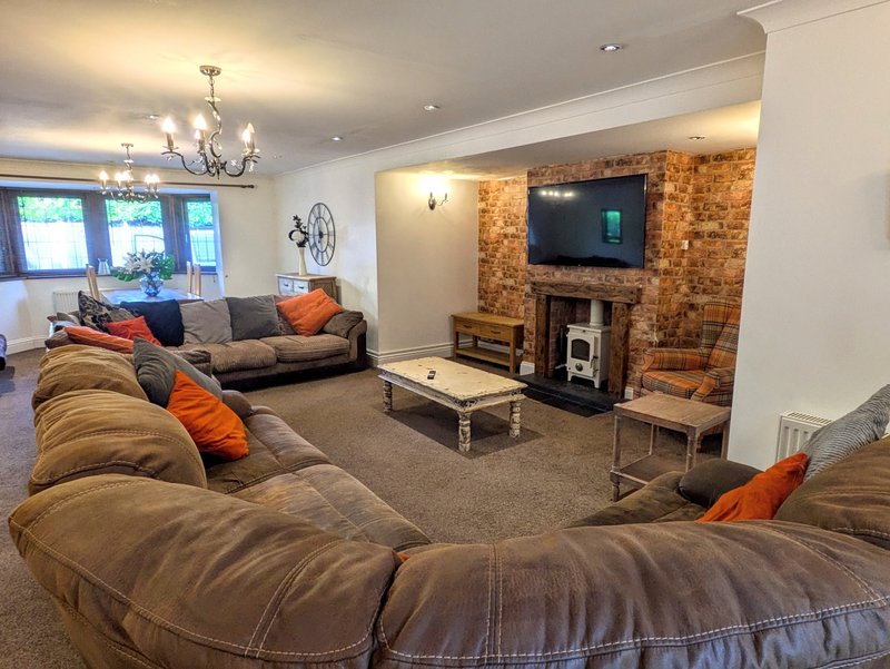 A large, sociable living room with generous seating for  guests, including a substantial corner/sectional sofa, additional sofas and an armchair.