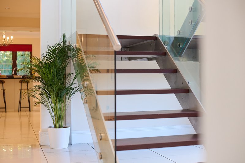 A modern open staircase with glass balustrading, timber treads and contemporary metal detailing, creating a bright and stylish connection between the property's floors.