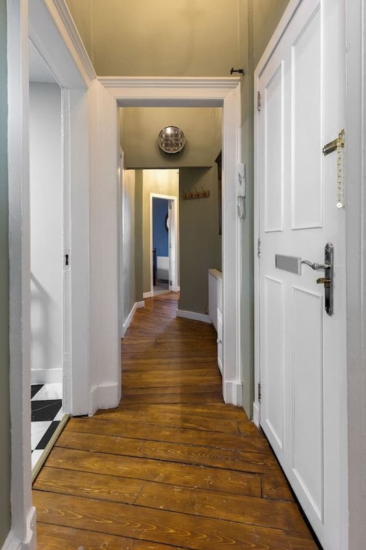Long hallway with wooden floors, white doors, and cream-colored walls and ceiling