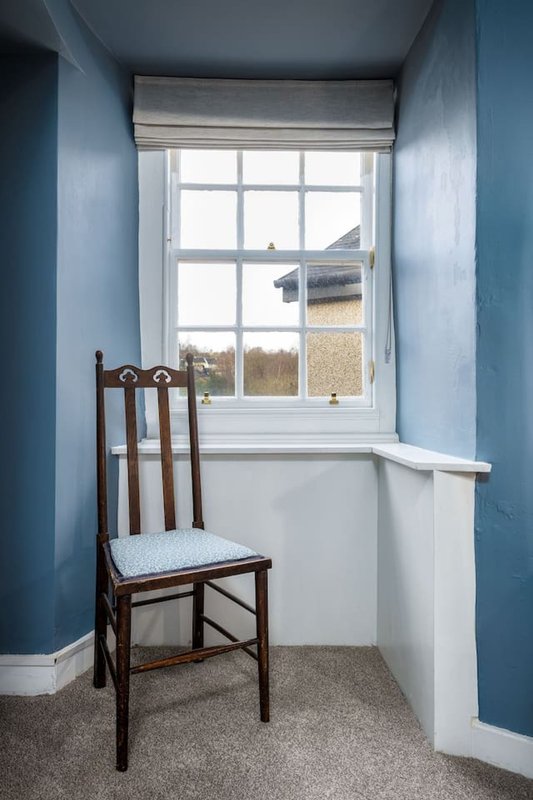 Small alcove with wooden chair, window overlooking countryside, blue and white walls