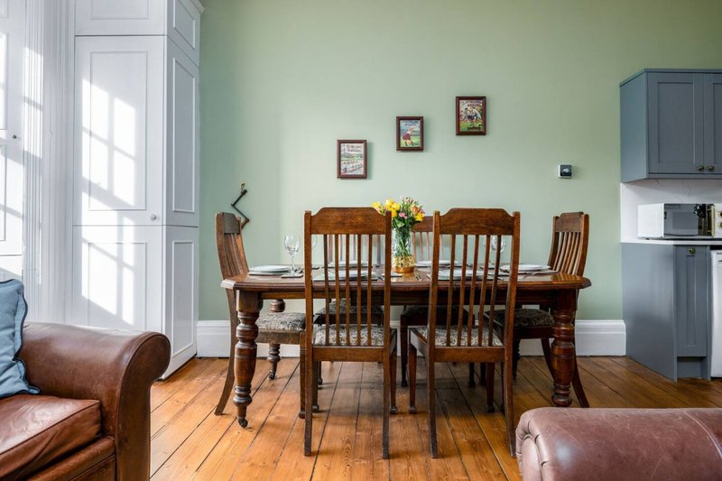 Dining room with wooden table, chairs, leather armchairs and mint green walls