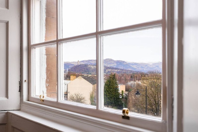 Large window with mountain view, white frame and sill, residential countryside landscape