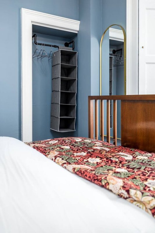 Bedroom with double bed, wooden headboard, mirror, closet organizer and blue walls