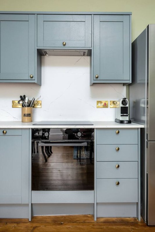 Modern kitchen with blue cabinetry, built-in oven, white countertop and gold hardware