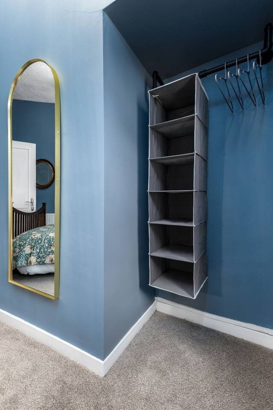 Modern walk-in wardrobe with arched mirror, built-in shelving and hanging rail
