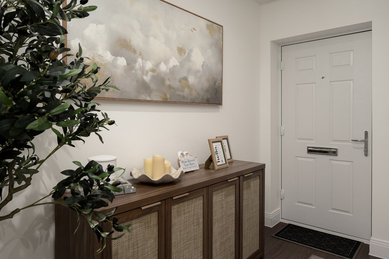 Hallway entryway with white door, wooden storage cabinet, plant, framed artwork and candles