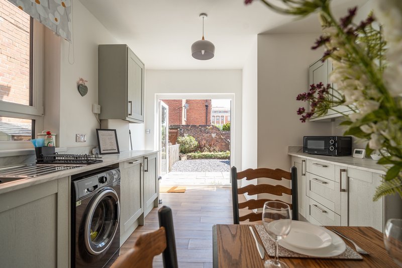 Kitchen diner with cream cabinets, washing machine, wooden dining table and garden view