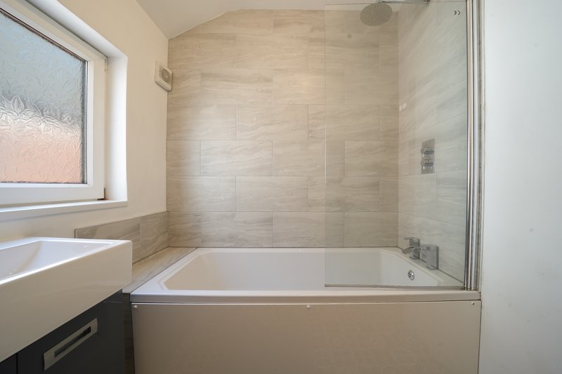 Modern bathroom with bathtub, glass shower screen, sink and window