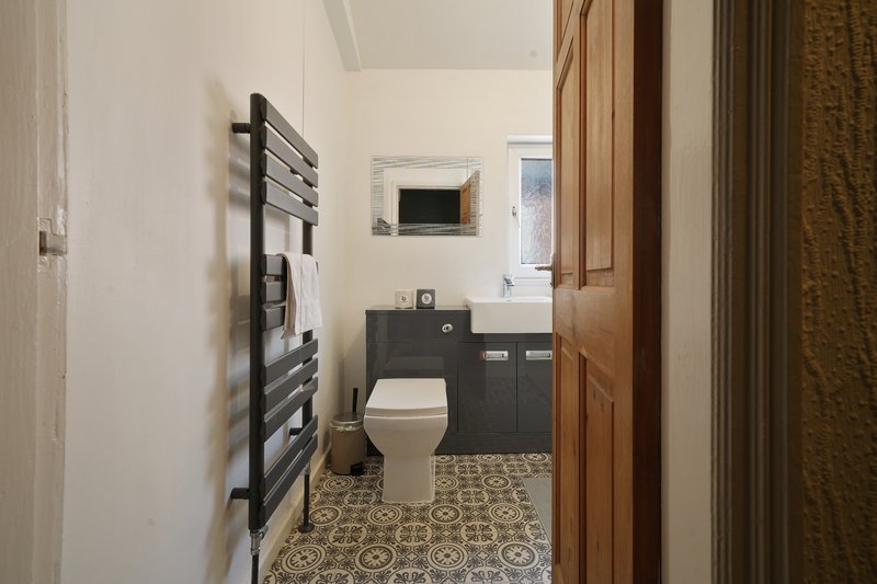 Modern bathroom with toilet, vanity sink, heated towel rail and patterned floor tiles