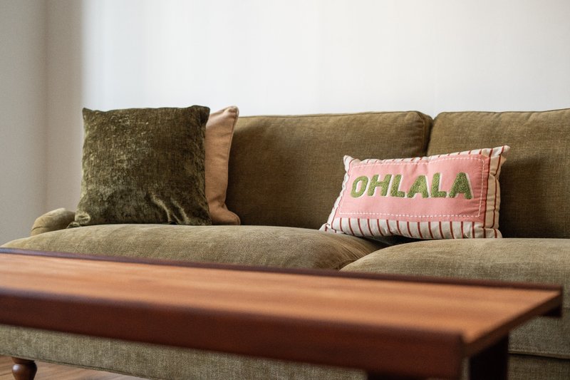 Olive-green sofa with decorative cushions and wooden coffee table in living room