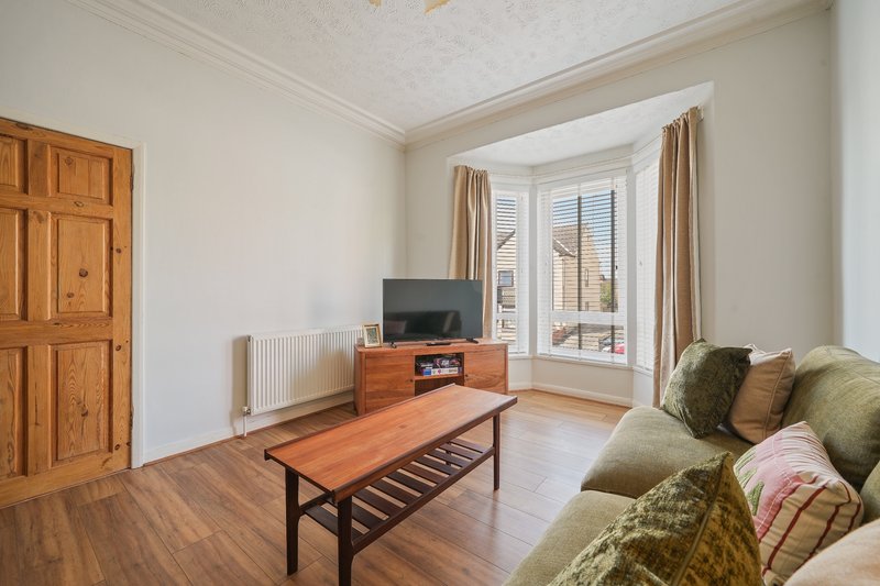 Bright living room with wooden floor, sofa, TV unit, coffee table and bay window