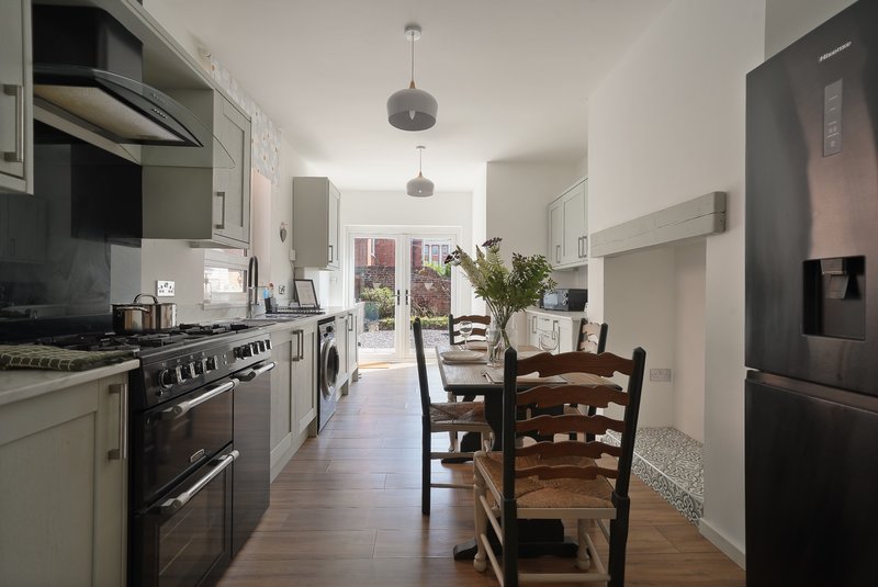 Modern kitchen with cream cabinetry, black range cooker, dining table and chairs, opens to garden view