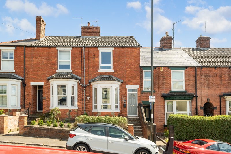 Brick terraced house with bay windows, front garden, driveway and parked cars