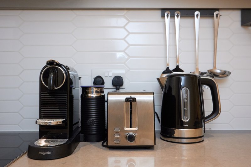 Kitchen counter with coffee machine, toaster, kettle and cooking utensils