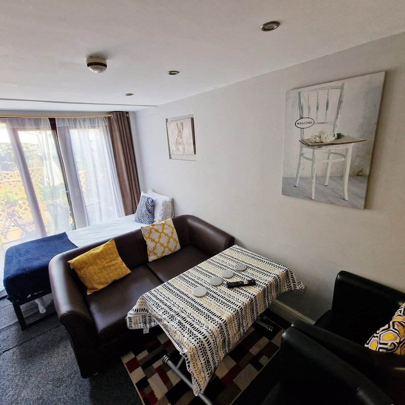 Modern living room with black sofa, patterned throw, cushions, window seat and wall art