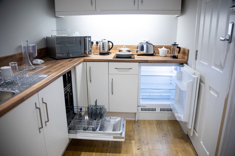 Modern kitchen with white cabinetry, wooden worktops, integrated appliances and kettle