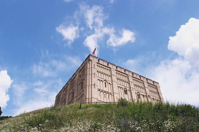 Historic stone building on hillside with manicured landscaping and blue sky