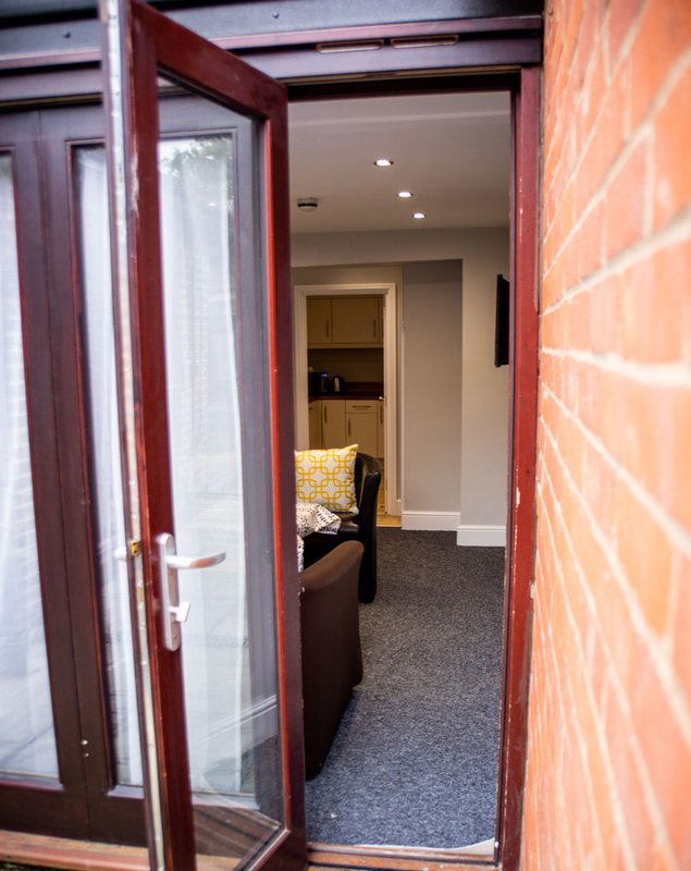 Hallway entrance with red brick exterior wall, dark wooden door frame, and carpeted corridor interior