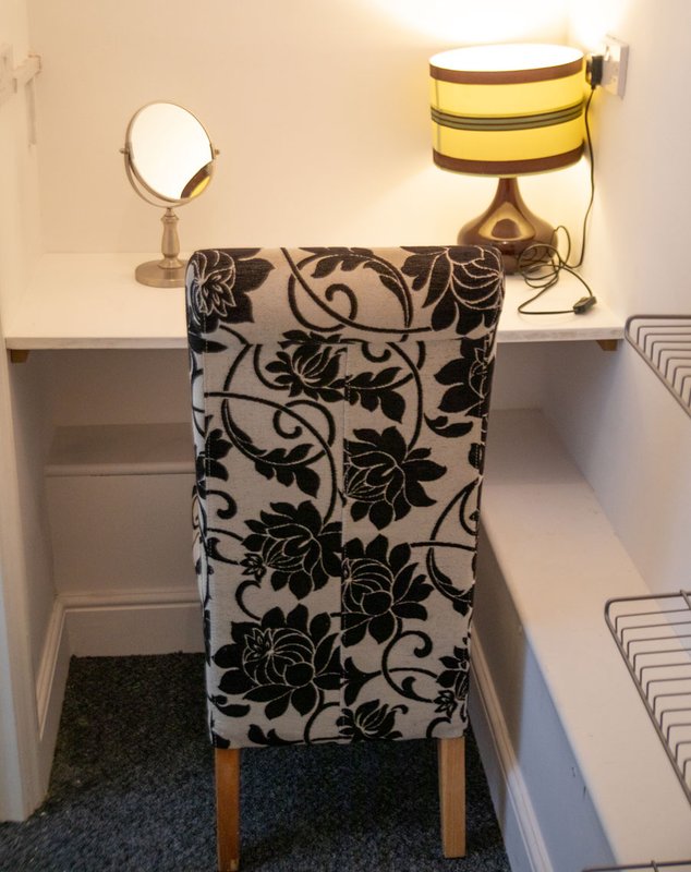 Bathroom shelf with mirror, decorative chair, and toiletries storage