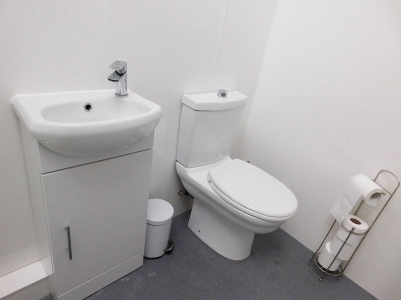 Modern bathroom with white sink vanity, toilet, and toilet paper holder