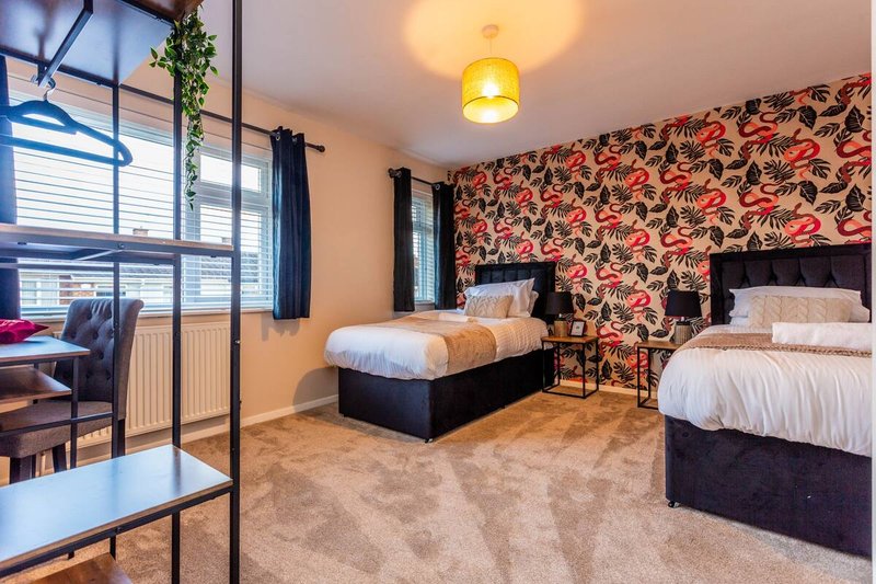 Spacious bedroom with two beds, patterned wallpaper, large windows and pendant lighting