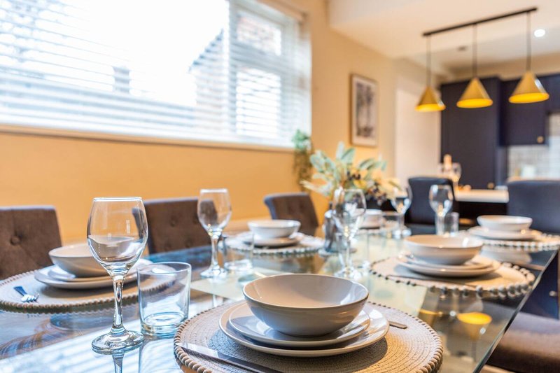 Dining room with set table, place settings, wine glasses, and yellow pendant lights
