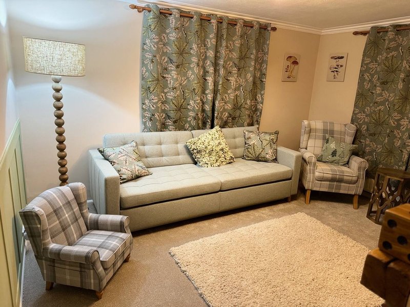 Living room with cream sofa, patterned armchairs, patterned curtains and table lamp