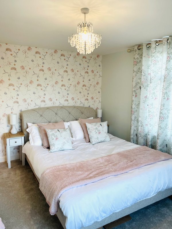 Bedroom with double bed, floral wallpaper, crystal pendant light, and matching curtains