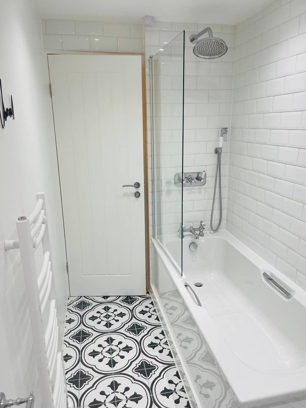Modern bathroom with walk-in shower, white subway tiles, patterned floor tiles, and rainfall showerhead