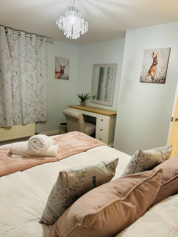 Bedroom with double bed, cushions, dressing table, mirror, chandelier and wall art