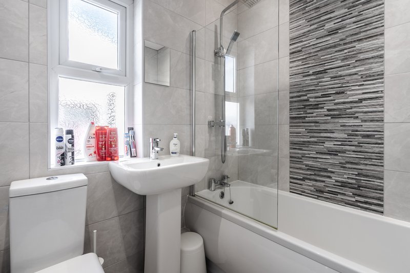 Modern bathroom with pedestal sink, shower enclosure, toilet and window
