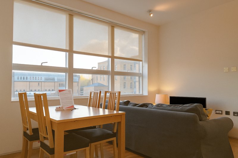 Modern apartment living room with dining table, wooden chairs, grey sofa and large windows overlooking city