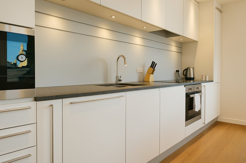 Modern white kitchen with built-in oven, sink, tap, utensil holder and wooden countertop