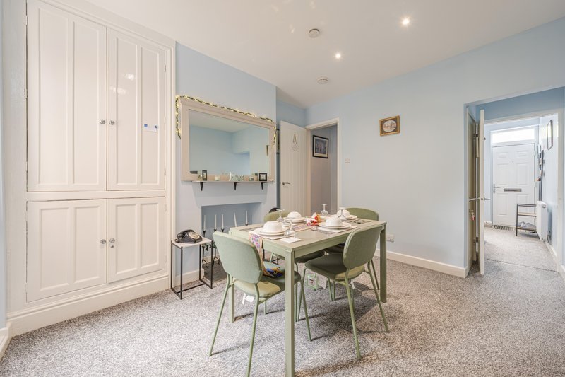 Light-filled bedroom with dining table, chairs, built-in wardrobes and mirror