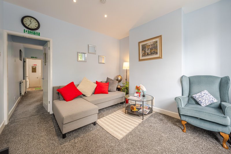 Bright living room with beige sectional sofa, blue armchair, striped rug and wall art