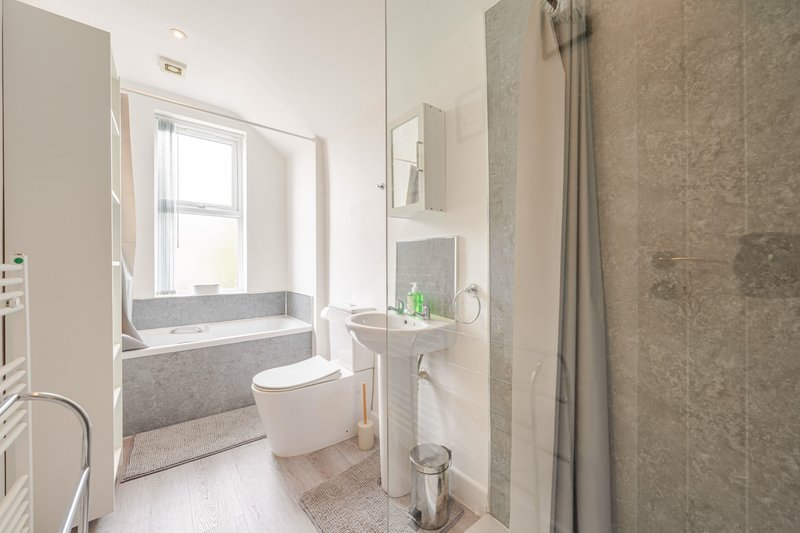 Modern bathroom with toilet, pedestal sink, bathtub and window with natural light