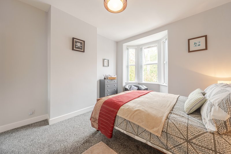Bright bedroom with double bed, red runner, neutral bedding, grey carpet and large window