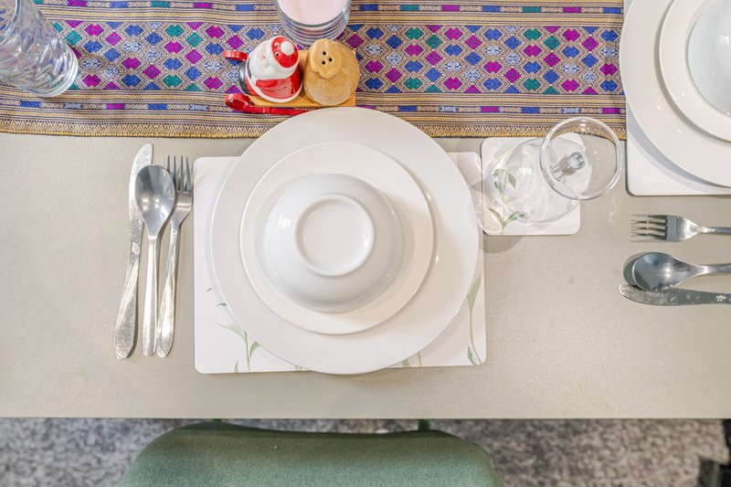 Overhead view of formally set dining table with white plates, cutlery, and colorful patterned table runner