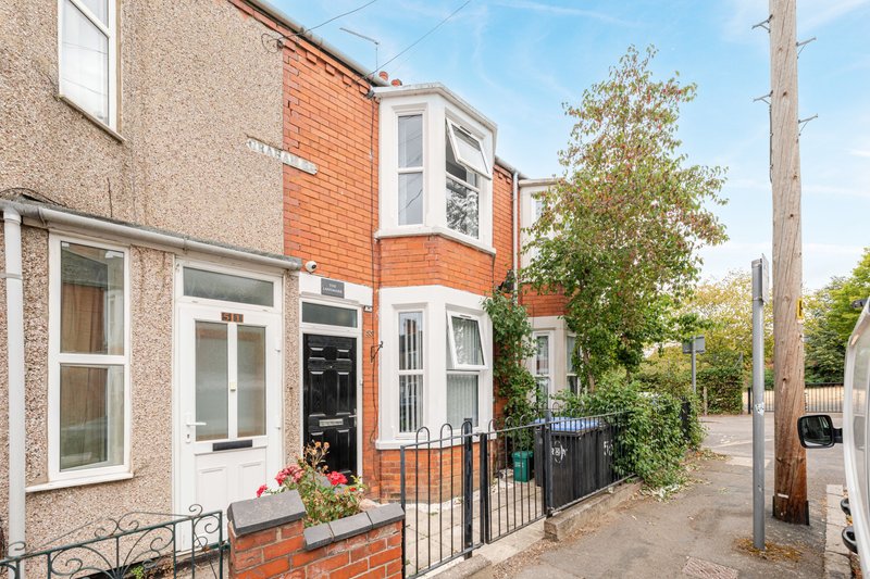 Brick terraced house exterior with black door, front garden and metal gate