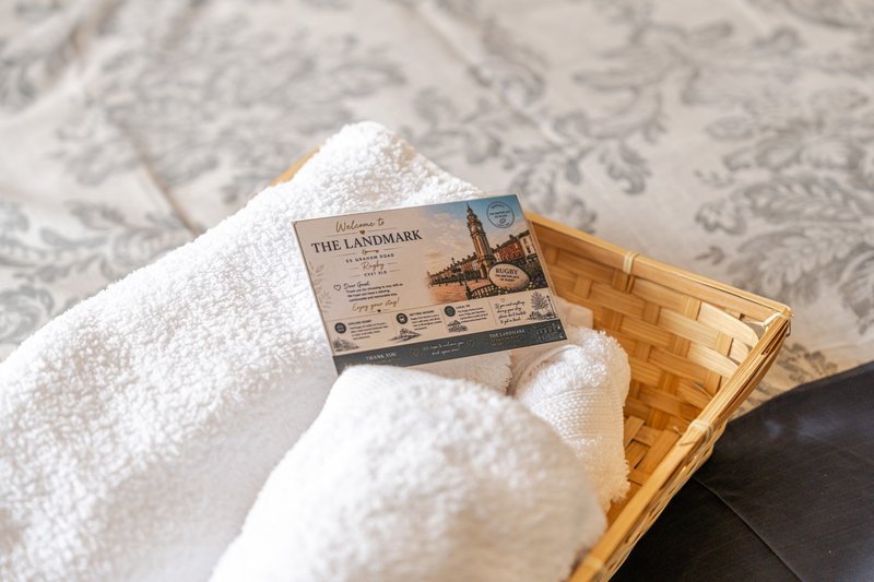 White rolled towels in wicker basket with branded soap package on patterned rug
