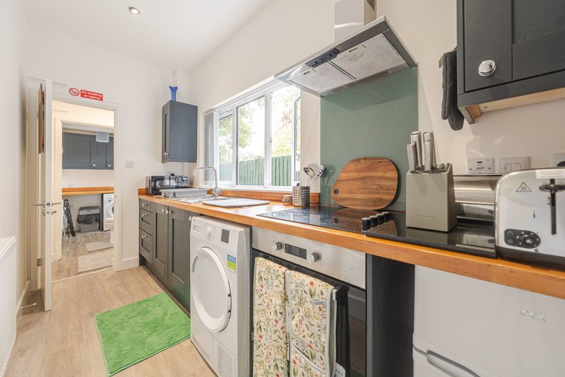 Modern kitchen with wooden countertops, stainless steel appliances, washing machine and green floor mat