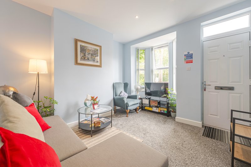 Bright living room with beige sofa, red cushions, armchair, coffee table and large windows