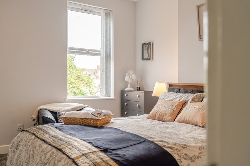 Bright bedroom with double bed, grey nightstand, window with garden view, and wall art