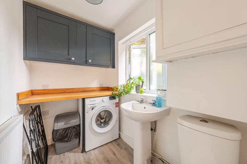 Compact utility room with washing machine, sink, toilet, and wooden countertop