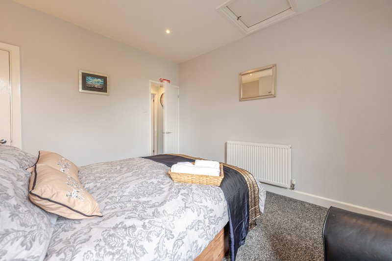 Bright bedroom with double bed, patterned bedding, radiator and cream walls
