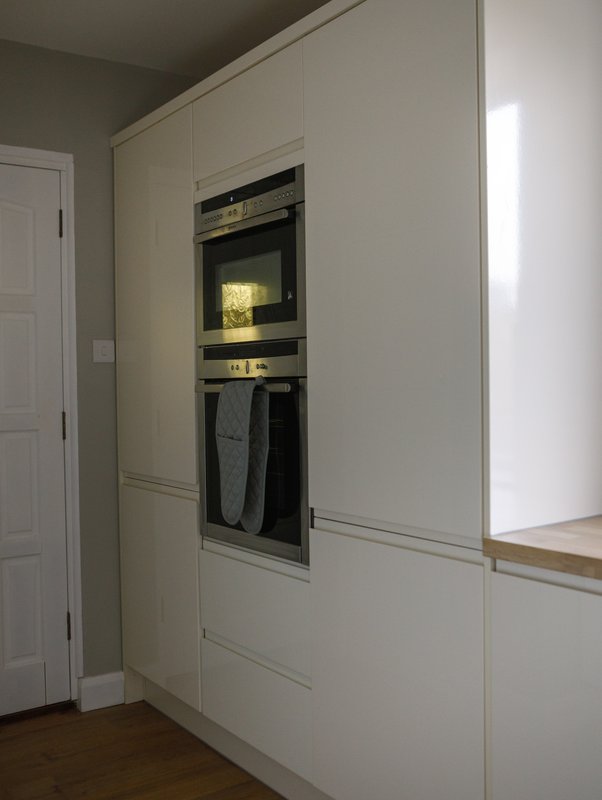 Modern kitchen with built-in cream cabinetry, integrated oven and microwave, wooden flooring