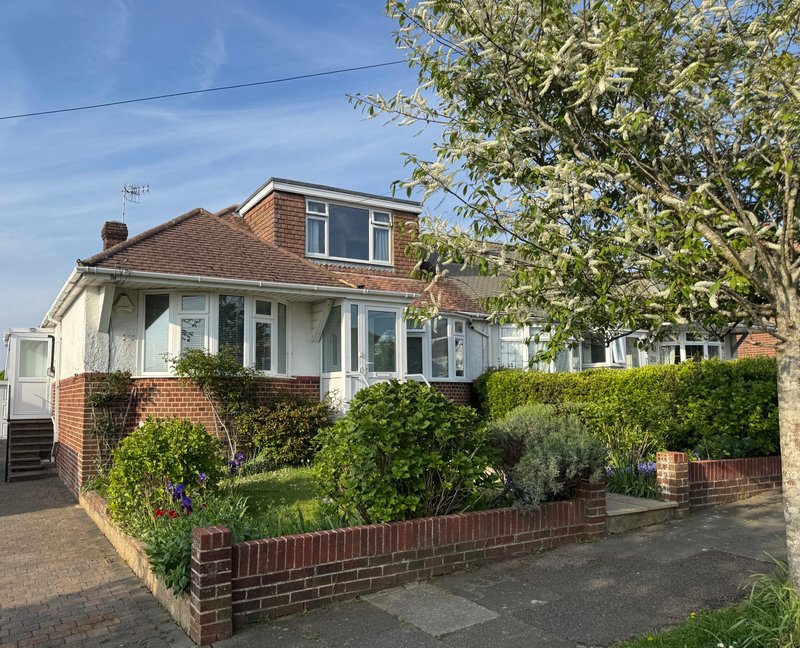 Brick semi-detached house with white render, front garden, hedge border and driveway
