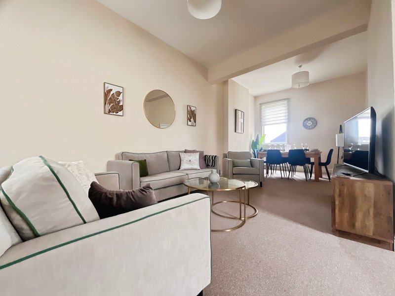 Open-plan living and dining area with cream sofas, wooden furniture, and blue dining chairs